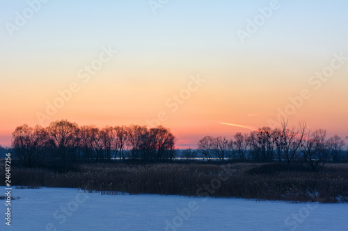 Sunset in the winter over the river covered with ice