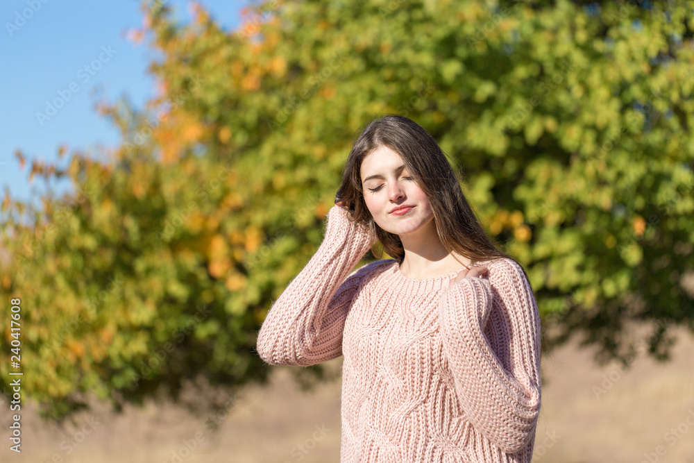 Portrait of pretty young woman in stylish knitted sweater standing on the golden autumn forest on sunny day Portrait of pretty young woman in stylish knitted sweater standing on the golden autumn forest on sunny day