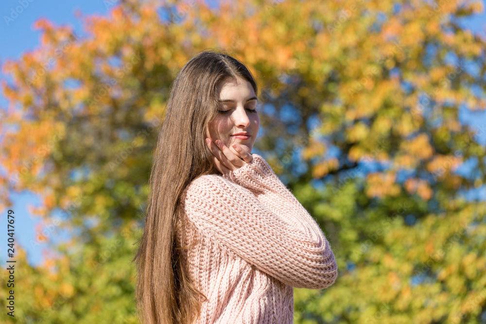 Portrait of pretty young woman in stylish knitted sweater standing on the golden autumn forest on sunny day Portrait of pretty young woman in stylish knitted sweater standing on the golden autumn forest on sunny day