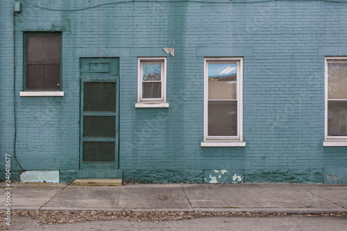 Green-blue brick building on empty sidewalk