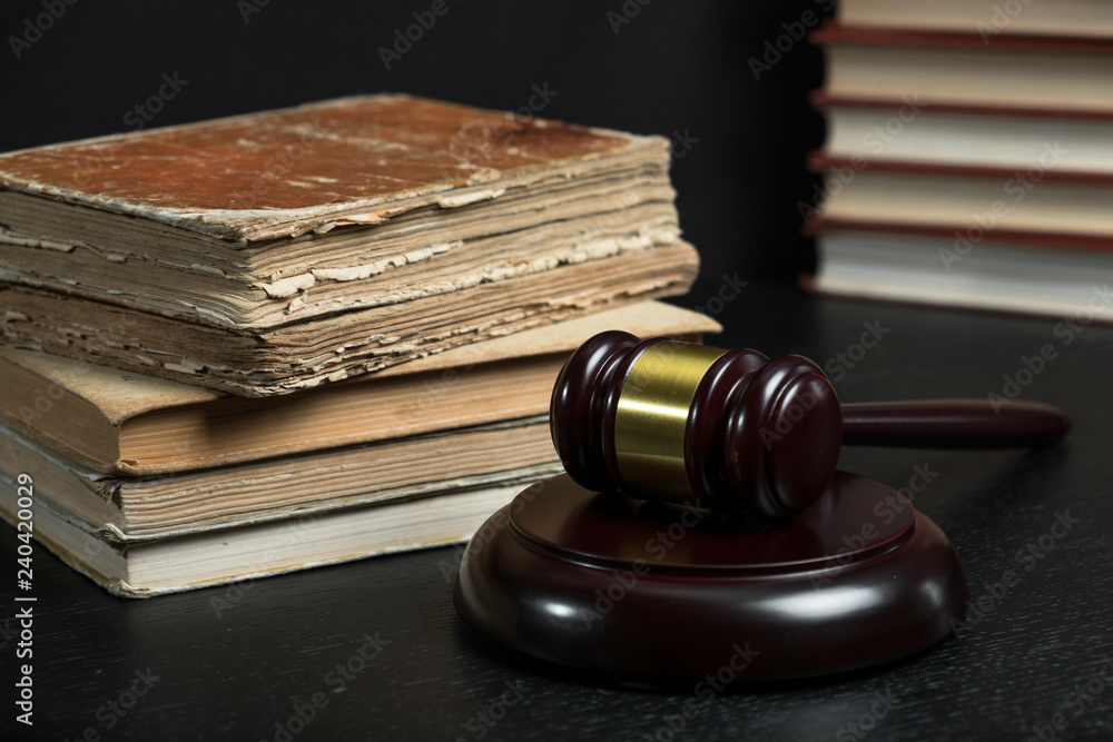 Judge gavel beside pile of books on wooden background Judge gavel beside pile of books on wooden background