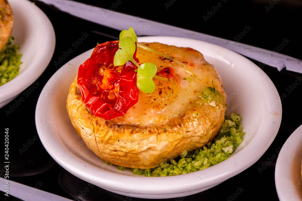 The champignon baked with cheese is served with a tomato The champignon baked with cheese is served with a tomato