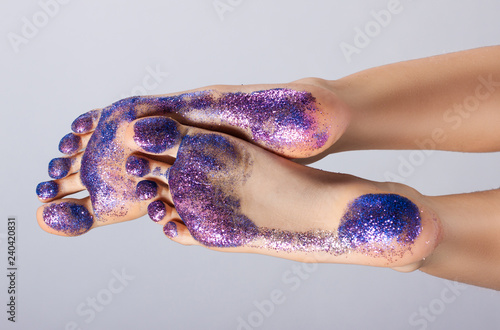female feet closeup. They are raised and covered with colorful sequins. Traces.