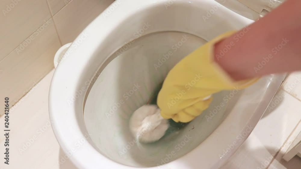 Woman hand in yellow rubber glove cleaning a dirty toilet bowl with a brush. Housekeeping, washing and cleaning bathroom concept Woman hand in yellow rubber glove cleaning a dirty toilet bowl with a brush. Housekeeping, washing and cleaning bathroom concept