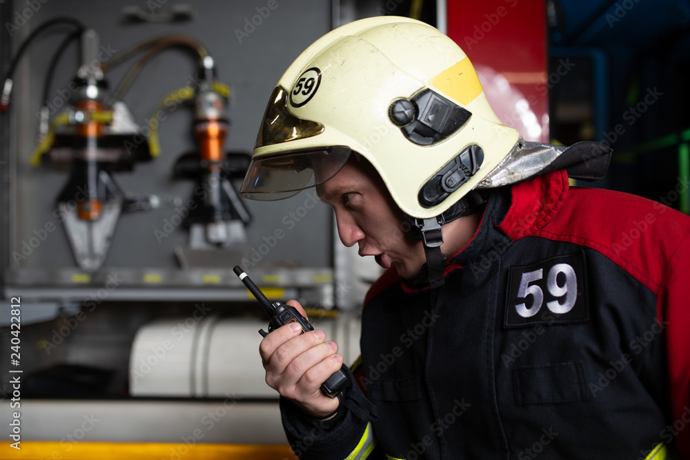 Image of man firefighter in helmet talking on radio Image of man firefighter in helmet talking on radio