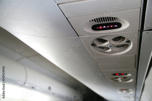 No Smoking and Fasten Seat Belt Symbols Above Air Vent Illuminated Overhead in Commercial Jet Waiting for Takeoff photo