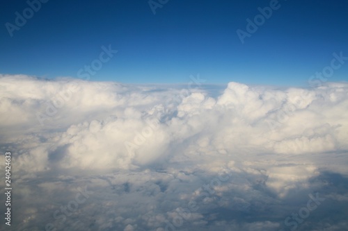Fototapeta Naklejka Na Ścianę i Meble -  Looking Out the Window of a Commercial Jet Down on a Bank of Enormous White Fluffy Clouds Heading North Up the East Coast of the United States toward Washington D.C. Late in the Afternoon