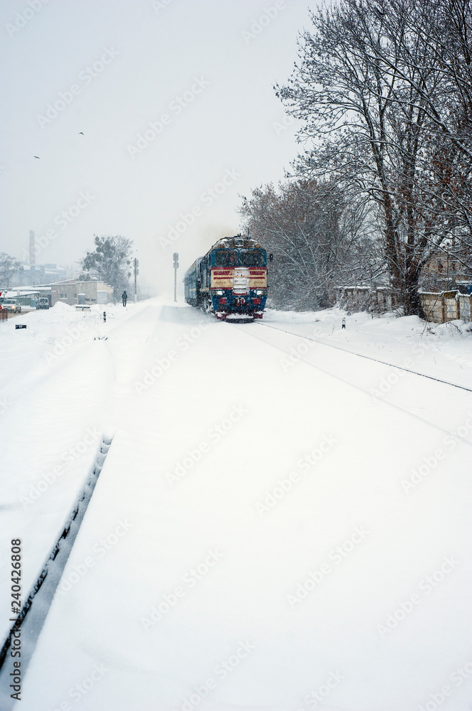 Train on the railway in heavy snow storm. Passenger train moves on the railway in winter in Ukraine. Train on the railway in heavy snow storm. Passenger train moves on the railway in winter in Ukraine.