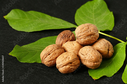 dry shelled walnut and green walnut leaves, on black background, dry shelled walnut and green walnut leaves,