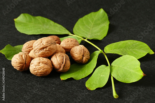 dry shelled walnut and green walnut leaves, on black background, dry shelled walnut and green walnut leaves,