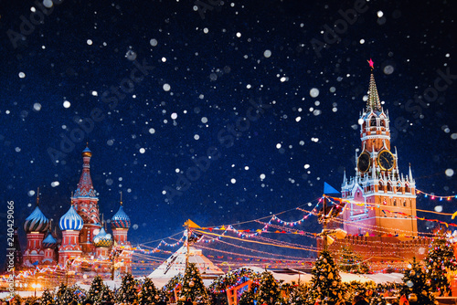 Saint Basil cathedral and Spasskaya Tower among new year festive decorations on Red Square in Moscow. Christmas fair in Kremlin of Russia at evening while snow falling.