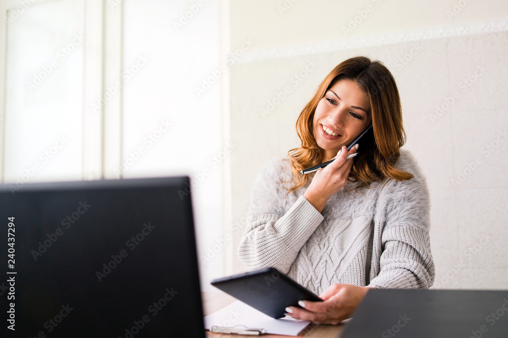 business woman working on her laptop and digital tablet while talking to the phone business woman working on her laptop and digital tablet while talking to the phone