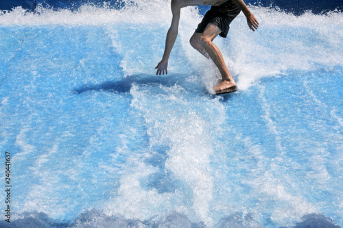Young man flowriding and flowboarding on artificial sheet waves