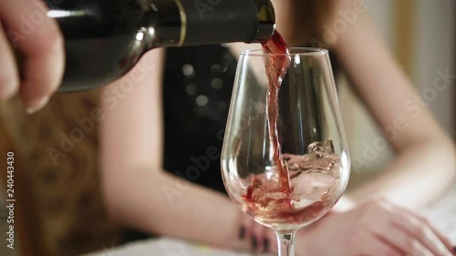 Waiter pouring red wine into glass. Close-up. Slow motion.