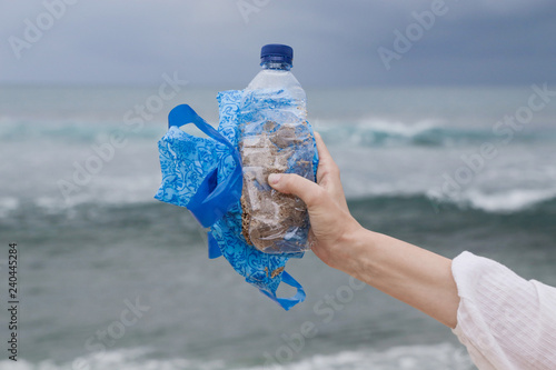 Plastic waste in hand against the blue sky background. The action of collecting trash from our beaches. Trash-free seas concept. Single-use plastic is a human addiction that is destroying our plan