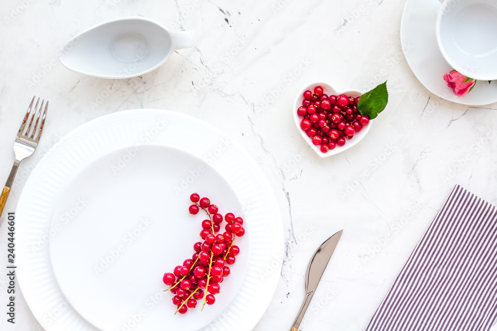 Elegant table setting with white plates, wineberry and floral decor on stone background top view Elegant table setting with white plates, wineberry and floral decor on stone background top view
