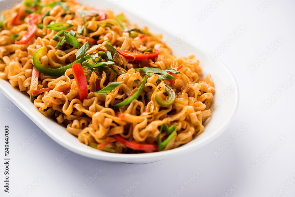 Schezwan veg noodles is a spicy and tasty stir fried flat Hakka noodles with sauce and veggies. served with chopsticks. selective focus Schezwan veg noodles is a spicy and tasty stir fried flat Hakka noodles with sauce and veggies. served with chopsticks. selective focus