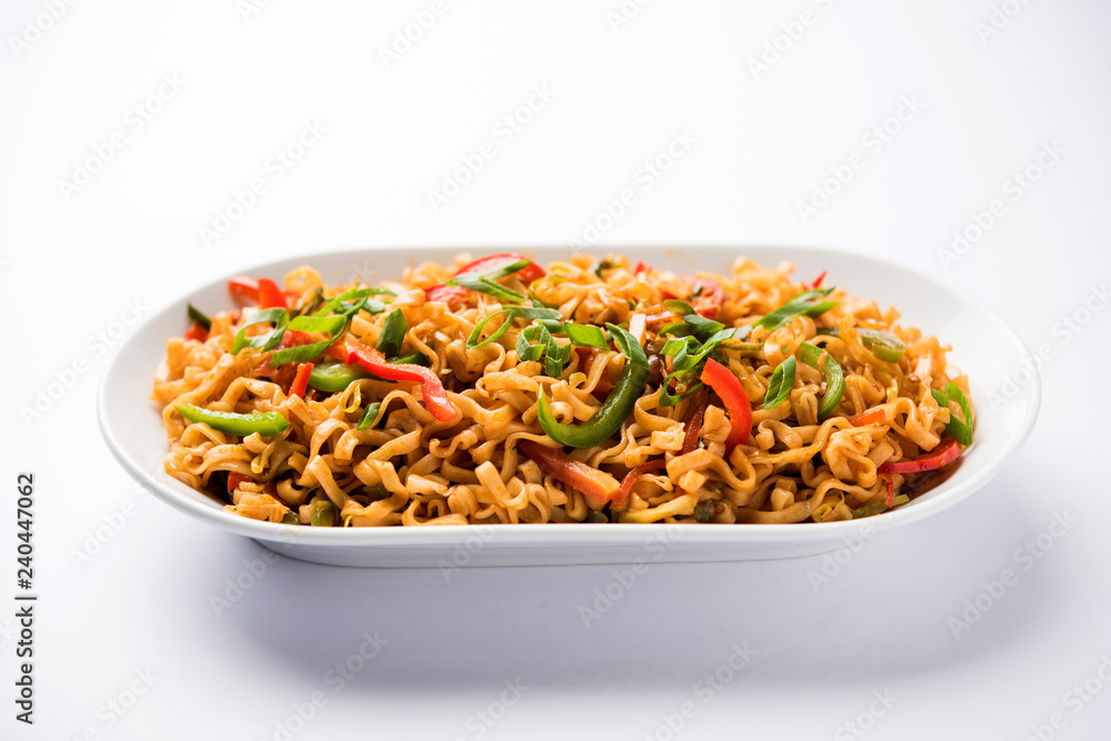 Schezwan veg noodles is a spicy and tasty stir fried flat Hakka noodles with sauce and veggies. served with chopsticks. selective focus Schezwan veg noodles is a spicy and tasty stir fried flat Hakka noodles with sauce and veggies. served with chopsticks. selective focus
