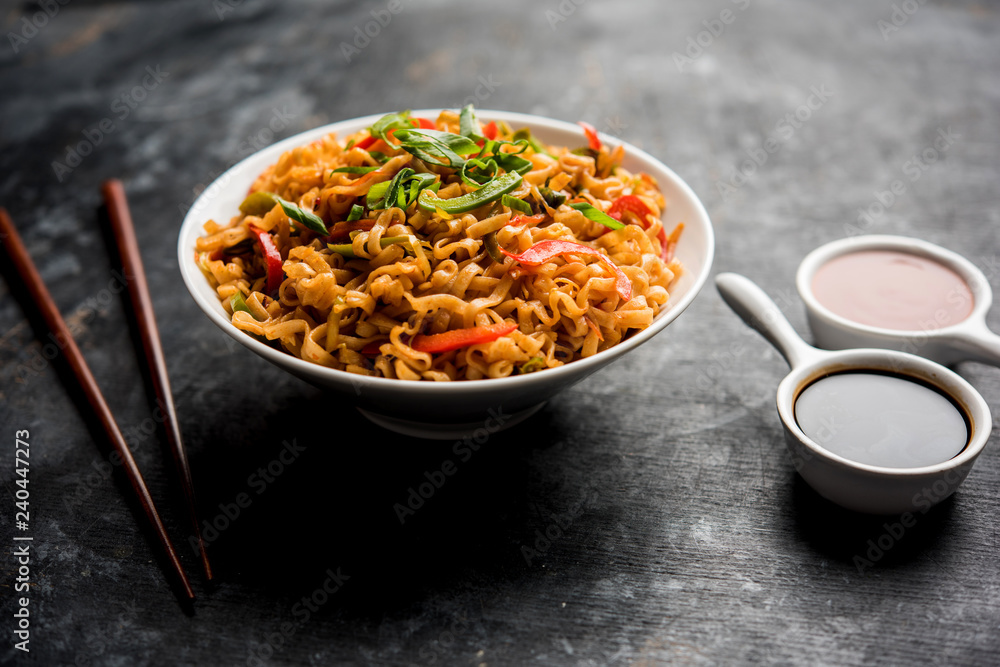 Schezwan veg noodles is a spicy and tasty stir fried flat Hakka noodles with sauce and veggies. served with chopsticks. selective focus Schezwan veg noodles is a spicy and tasty stir fried flat Hakka noodles with sauce and veggies. served with chopsticks. selective focus