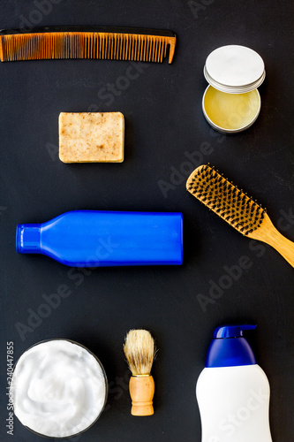 Instruments of male hairdresser with shampoo and comb in barbershop top view on black background mock up