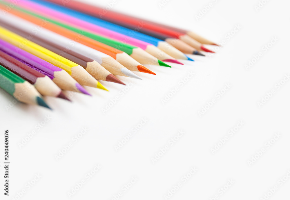 Closeup a row of colored pencils on white background with selective focus with copy space. Closeup a row of colored pencils on white background with selective focus with copy space.
