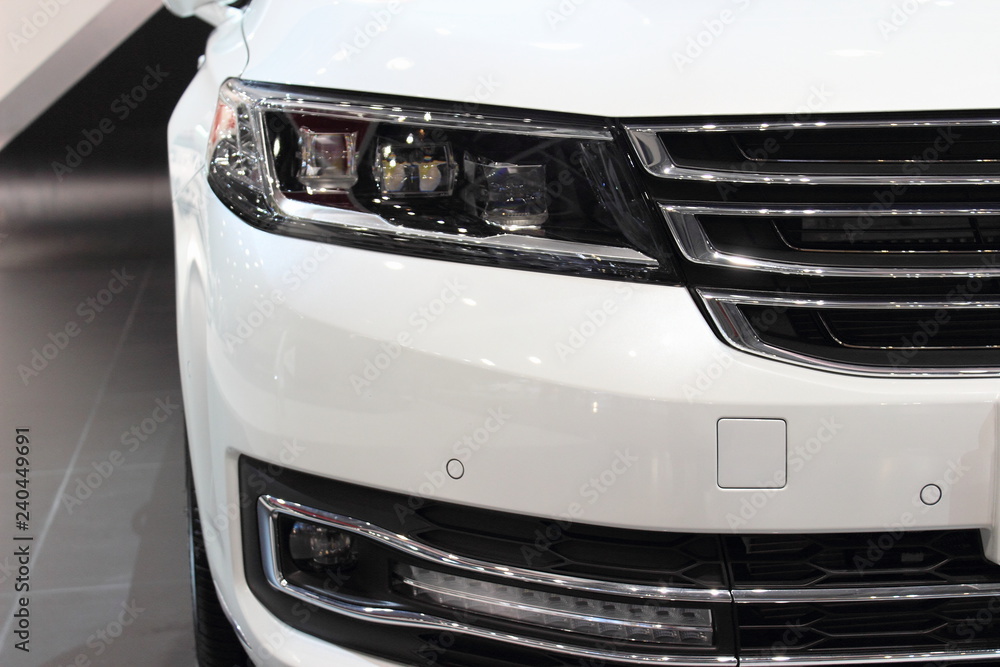 White front bumper with headlight of a car, Parking sensors and daytime running light close up