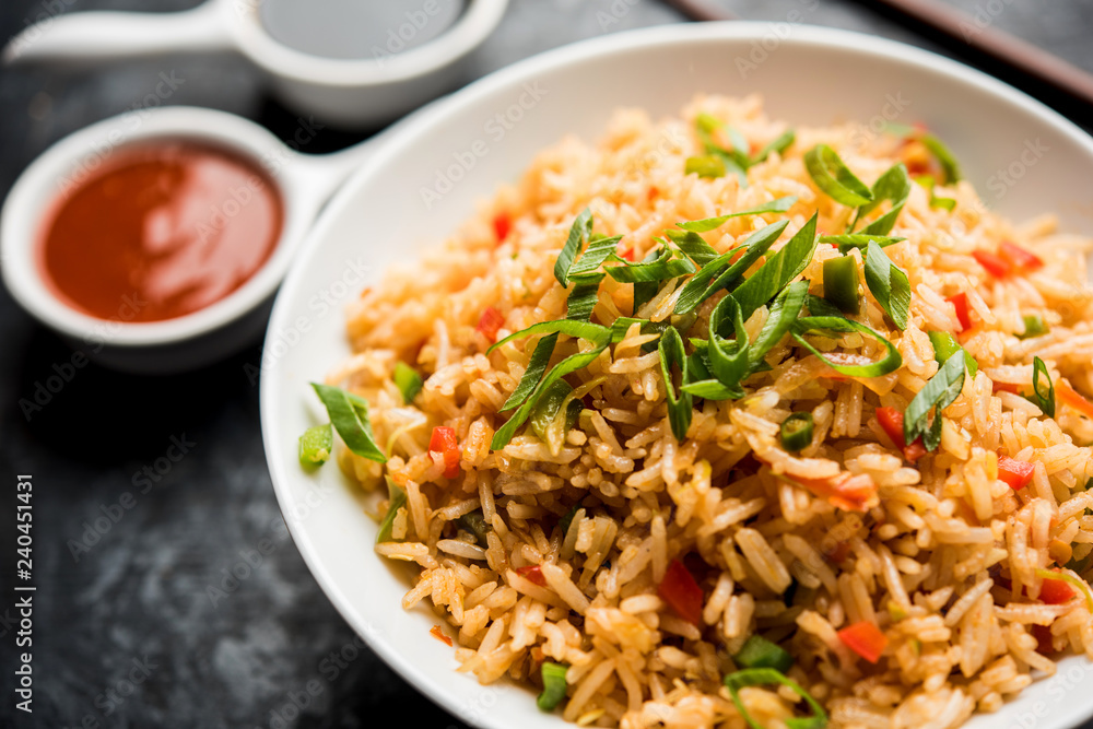 Schezwan Fried Rice Masala is a popular indo-chinese food served in a plate or bowl with chopsticks. selective focus Schezwan Fried Rice Masala is a popular indo-chinese food served in a plate or bowl with chopsticks. selective focus
