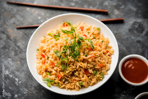 Schezwan Fried Rice Masala is a popular indo-chinese food served in a plate or bowl with chopsticks. selective focus