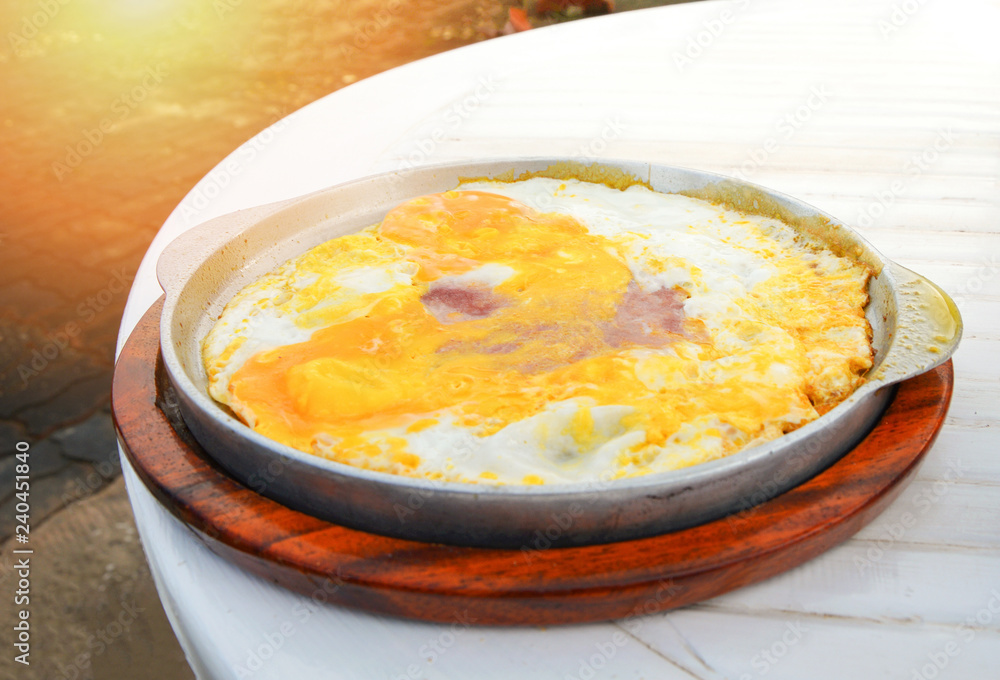 breakfast of fried eggs with ham in a frying pan on wood plate