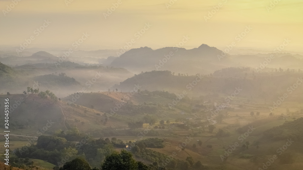 sunrise at Doi Mae Salong, beautiful mountains with many hills around with soft mist and yellow sun light in the sky background, Doi Mae Salong View Point, Chiang Rai, northern Thailand.