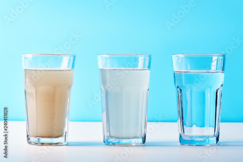 Water filters. Concept of three glasses on a white blue background. Household filtration system. photo