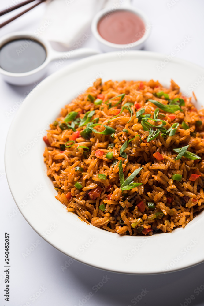 Schezwan Fried Rice Masala is a popular indo-chinese food served in a plate or bowl with chopsticks. selective focus Schezwan Fried Rice Masala is a popular indo-chinese food served in a plate or bowl with chopsticks. selective focus