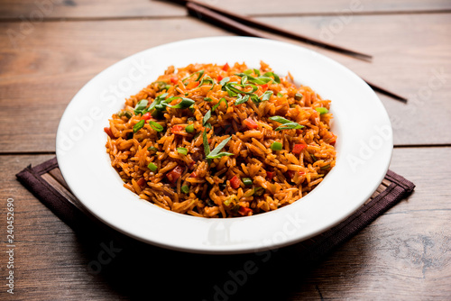 Schezwan Fried Rice Masala is a popular indo-chinese food served in a plate or bowl with chopsticks. selective focus