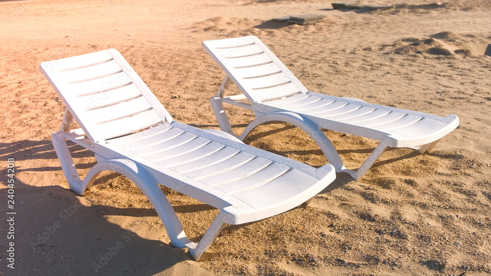 Two sunlongers on the sand beach in summer. Two sunlongers on the sand beach in summer.