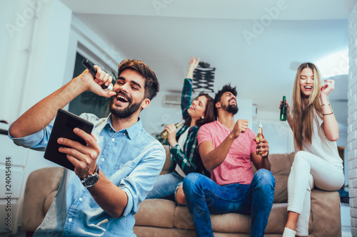 Group of friends playing karaoke at home. Concept about friendship, home entertainment and people © Mediteraneo