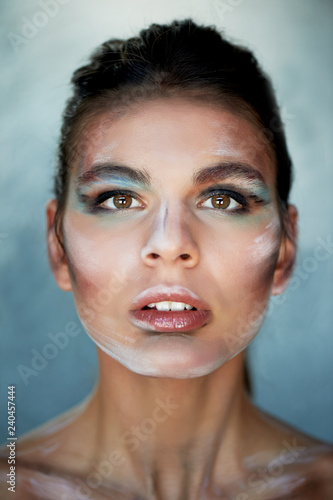 Girl model with creative makeup, paint strokes on the face. Creative person.Lips ajar, head slightly thrown back