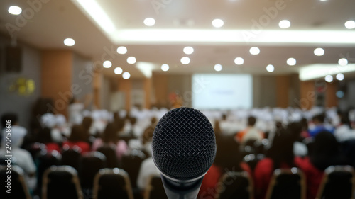 Microphone over the Abstract blurred photo of conference hall or seminar room with attendee background,Small Business training concept,Public speaking