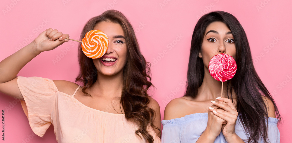 Two attractive fancy friends holding colorful lollipops Two attractive fancy friends holding colorful lollipops