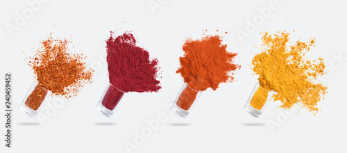 Glass jars with various spices flying on white background