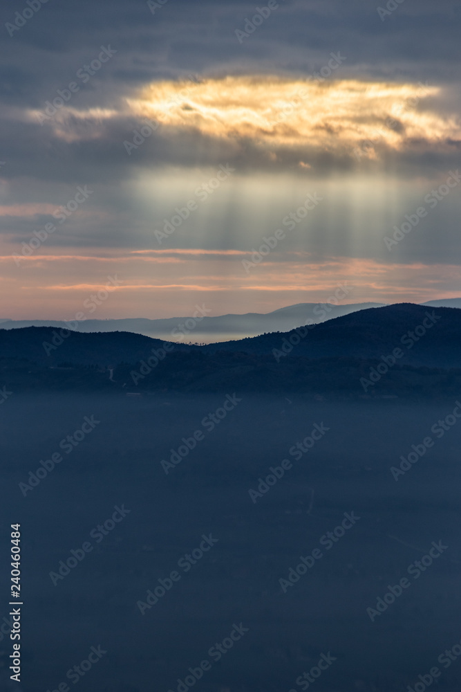 Sunray shines through clouds over the mountains and a sea of fog