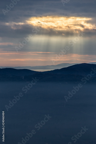 Sunray shines through clouds over the mountains and a sea of fog © Massimo