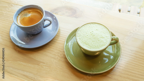 A cup of hot coffee and hot green tea on a wooden table in a morning.