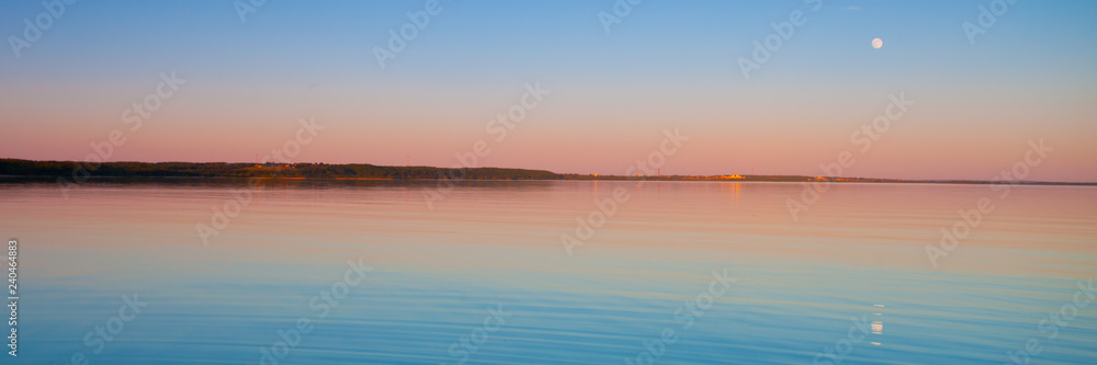 Panorama of the turquoise dawn of the sky and water of pink and turquoise color, the sun rises
