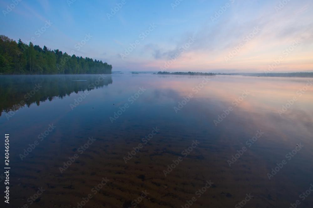 Dawn on the lake. In the foreground through the water you can see the sand