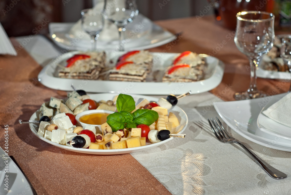 Delicious dishes on the table in the restaurant. serving table. Different kinds of cheese with honey on a plate. Delicious dishes on the table in the restaurant. serving table. Different kinds of cheese with honey on a plate.