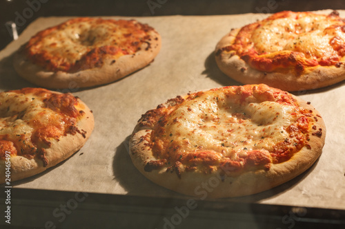 Four little pizza margherita with tomato sauce and mozzarella baking in the electric oven