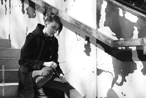 strong, laid back, cool girl, tomboy in black and white street style scene. Outdoor fashion images of beautiful tomboy. Hip blogger girl lgbt