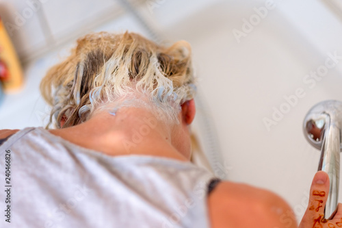 Blond woman shampooing her hair in a basin
