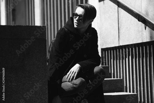 strong, laid back, cool girl, tomboy in black and white street style scene. Outdoor fashion images of beautiful tomboy. Hip blogger girl lgbt