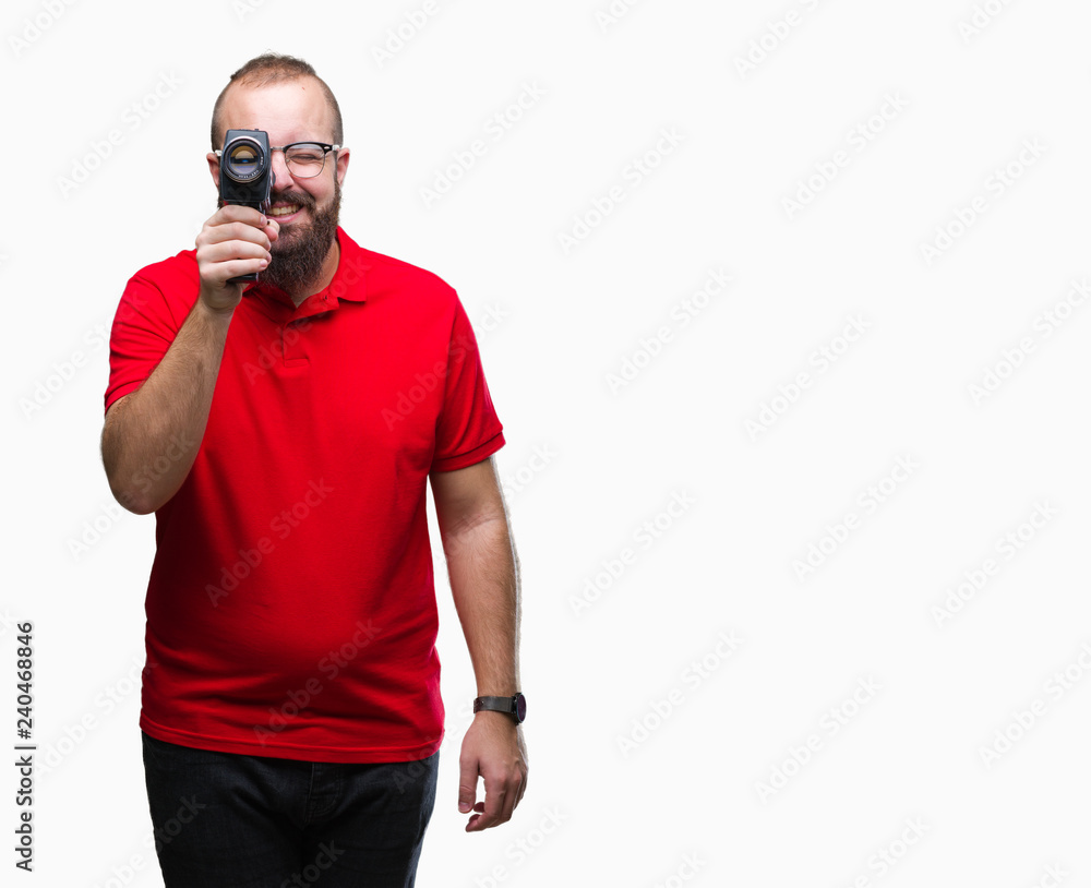 Young caucasian hipster man filmming using retro video camera over isolated background with a happy face standing and smiling with a confident smile showing teeth Young caucasian hipster man filmming using retro video camera over isolated background with a happy face standing and smiling with a confident smile showing teeth